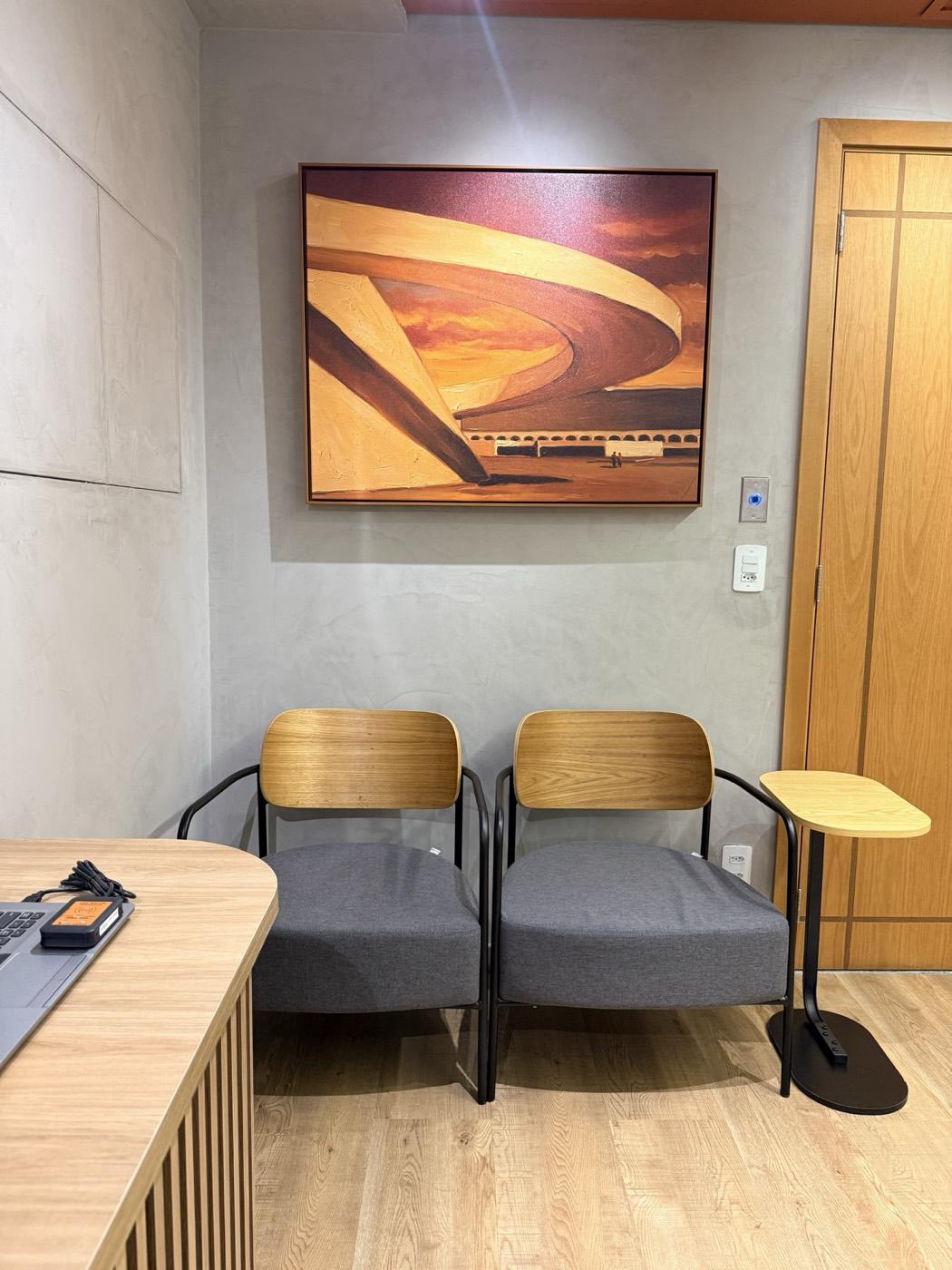 Área de espera com poltronas e quadro